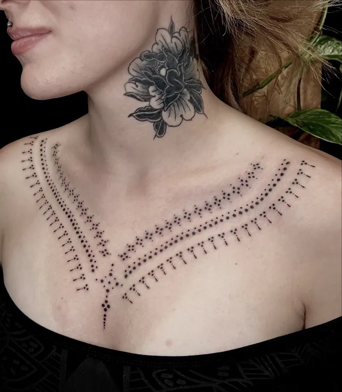 Ornamental hand-poked necklace across the collarbones