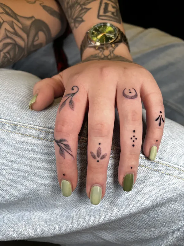 Hand-poked ornamental finger adornments with fine botanical detail