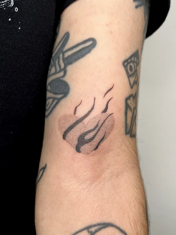 Hand-poked flame motif on the inner forearm