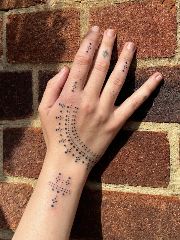 Hand-poked dotwork adornment across the back of the hand