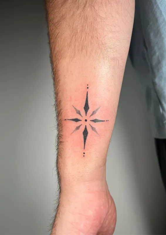 Fine line compass star hand-poked on the forearm