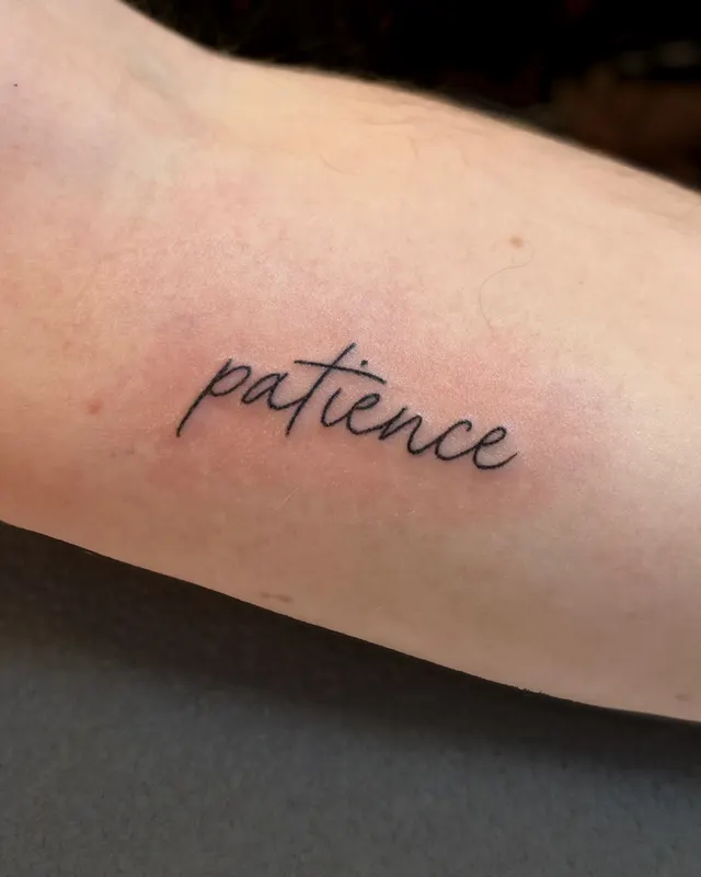 Fine line script reading patience on the forearm