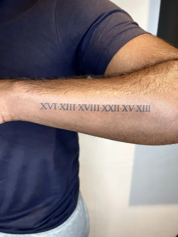 Hand-poked Roman numerals along the inner forearm