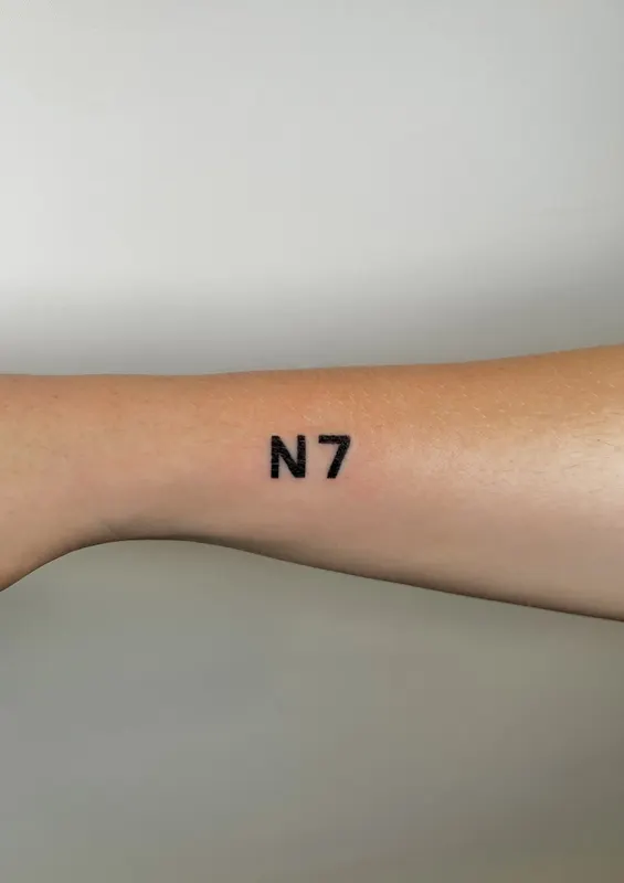 Small hand-poked N7 lettering on the forearm